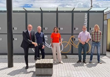 5 Menschen stehen vor Fahrradboxen